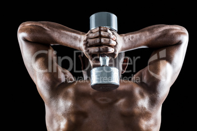 Rear view of muscular man lifting dumbbell behind head