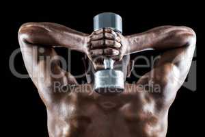 Rear view of muscular man lifting dumbbell behind head