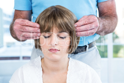 Woman with eyes closed receiving reiki from male therapist