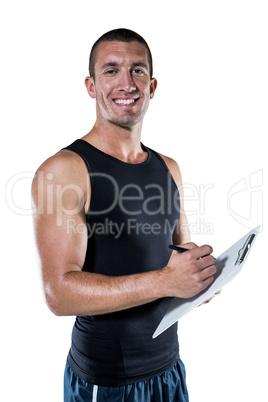 Smiling sports coach writing on clipboard