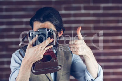 Hipster showing thumbs up gesture while photographing