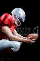 American football player crouching while holding ball