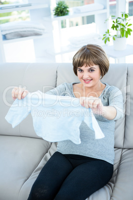 Portrait of pregnant woman holding baby clothes