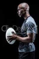 Profile view of confident sportsman holding rugby ball