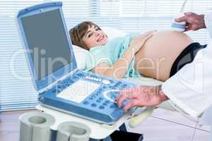 Happy pregnant woman lying on bed for ultrasound test