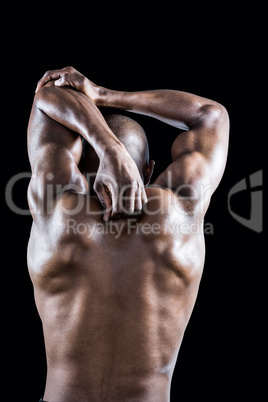 Rear view of muscular athlete stretching