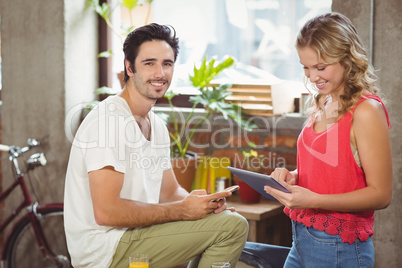 Portrait of businessman with smart phone while woman using digit