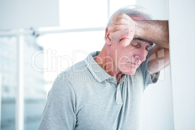 Sad mature man leaning on wall