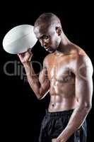 Concentrated shirtless athlete holding rugby ball