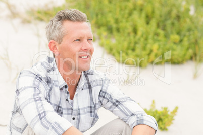 Smiling man sitting on the sand