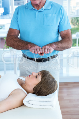 Pregnant woman relaxing while therapist performing reiki