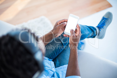 High angle view of man holding smartphone while sitting on sofa