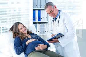 Male doctor showing document to pregnant woman in clinic