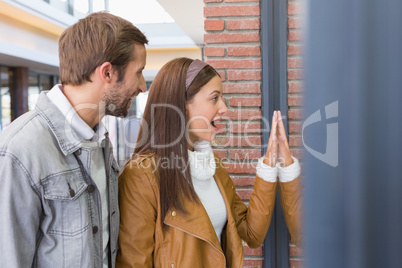 Young happy smiling couple looking at a window
