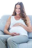 Happy pregnant woman sitting on sofa