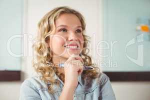 Smiling thoughtful businesswoman standing in office