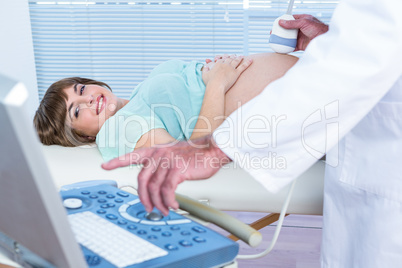Doctor showing ultrasound monitor to happy pregnant woman