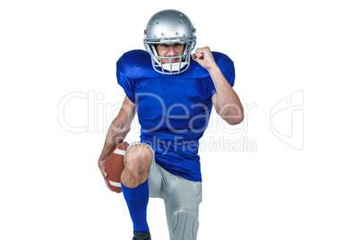 American football player standing on one leg while holding ball