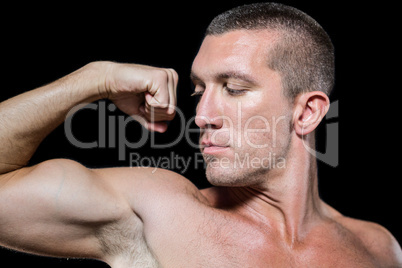 Close-up serious shirtless athlete flexing muscles