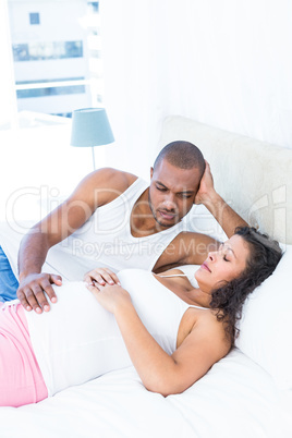 Affectionate man looking at pregnant wife sleeping on bed
