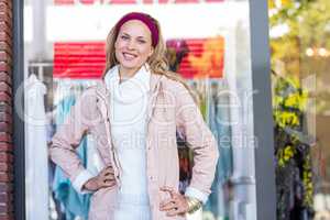 Smiling woman with hands on hips in front of window