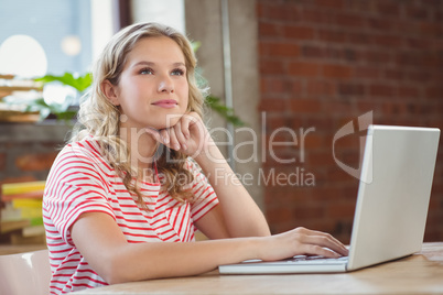 Thoughtful woman using laptop in office