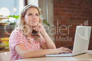 Thoughtful woman using laptop in office