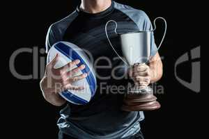 Midsection of successful rugby player holding trophy and ball