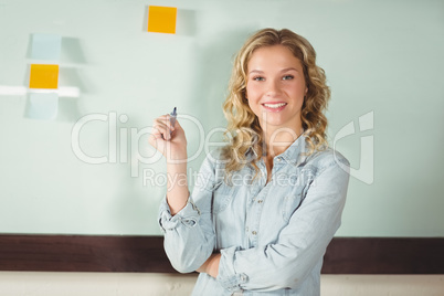 Portrait of smiling businesswoman standing by glass board in off