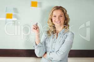 Portrait of smiling businesswoman standing by glass board in off