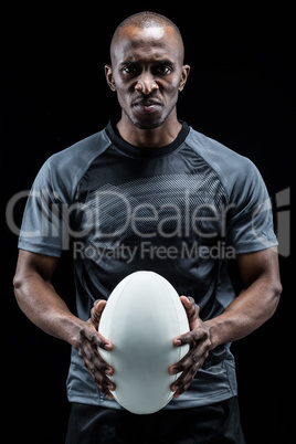 Portrait of serious athlete holding rugby ball