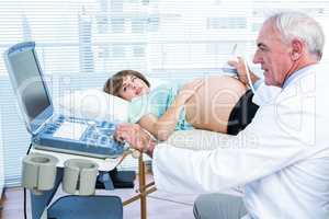 Pregnant woman and doctor looking at scan machine