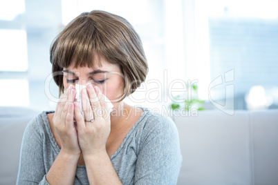 Woman sitting on a sofa about to sneeze