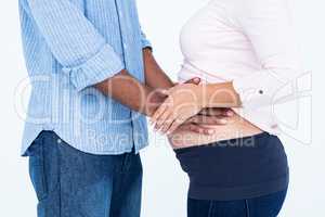 Midsection of husband touching belly against white background