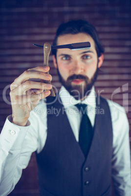 Portrait of serious hipster holding razor