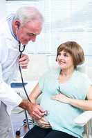 Doctor examining pregnant woman with stethoscope
