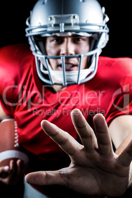 Portrait of American football player defending while holding bal