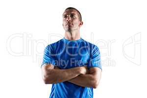 Confident rugby player looking away with arms crossed