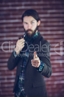 Defocused portrait of serious man with smoking pipe pointing fin