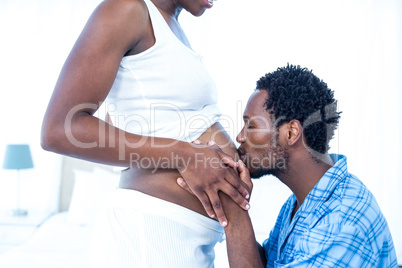 Affectionate man kissing belly of his pregnant wife