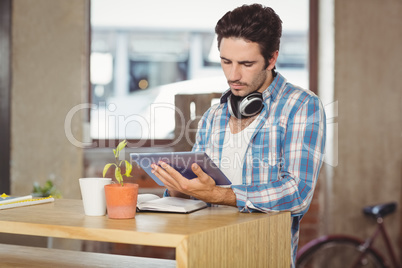 Businessman using digital tablet while standing by table in offi