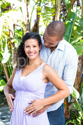 Portrait of happy pregnant wife with husband touching belly