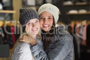 Two beautiful friends with winter clothes smiling at camera