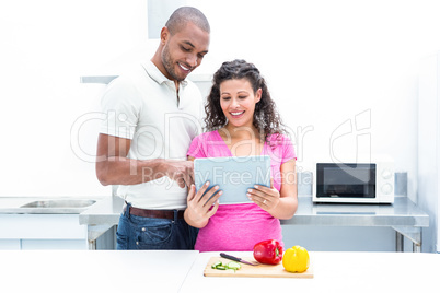 Happy couple using digital tablet in kitchen