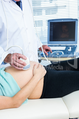 Doctor performing ultrasound on pregnant woman