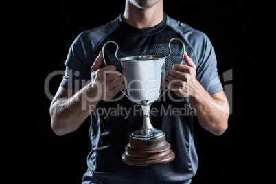Victorious rugby player holding trophy