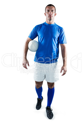 Portrait of rugby player looking away while holding ball aside