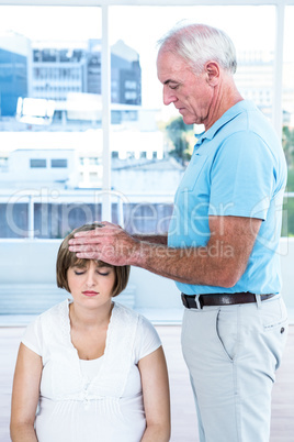 Male masseur massaging head of pregnant woman