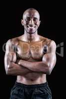 Portrait of happy shirtless athlete standing with arms crossed