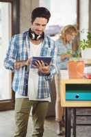 Happy businessman holding digital tablet in creative office